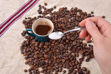 Hand of a woman mixing the sugar in a green cup of coffee. Roast