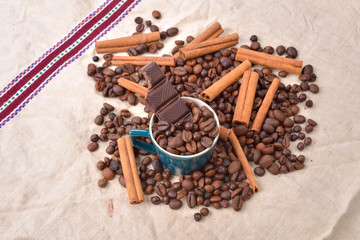 Cup of coffee with cinnamon sticks, bitten bar of chocolate on v