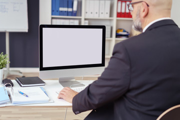 geschäftsmann am schreibtisch schaut auf seinen pc