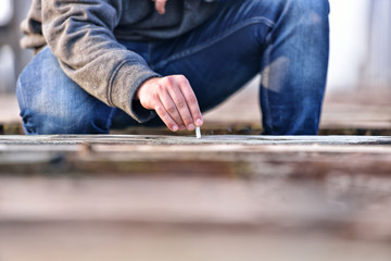 Hand of a young man extinguishing cigarette on a old bridge. Con