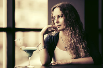 Sad beautiful woman with long curly hairs at restaurant