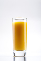 Glass of fresh orange juice and oranges on wooden table.