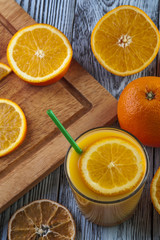 Fototapeta na wymiar Glass of fresh orange juice and oranges on wooden table.