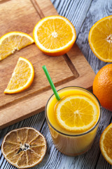 Fototapeta na wymiar Glass of fresh orange juice and oranges on wooden table.