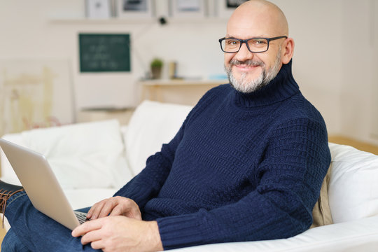 moderner älterer mann mit laptop auf dem sofa