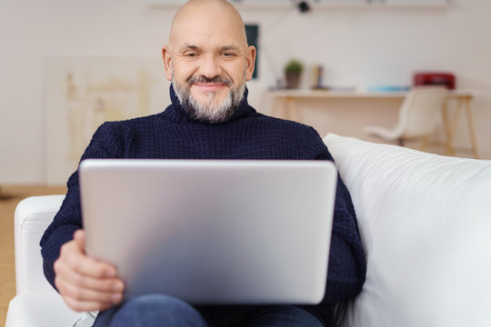 kreativer älterer mann mit laptop auf dem sofa