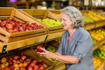 Smiling senior woman picking apple