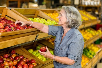 Smiling senior woman picking apples
