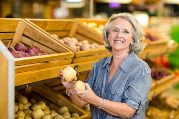 Smiling senior woman holding potatoes