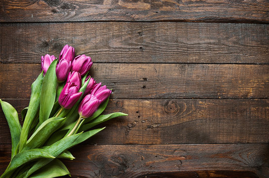 Pink, tulips bunch on dark barn wood planks background. Space for text, copy, lettering. Postcard template.