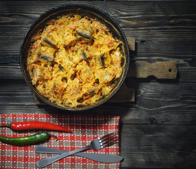 .Baked in a cast iron frying pan fish pollack , on a wooden table .