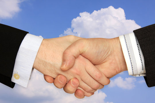 Businessmen shaking hands on a background of cloudy Sky 