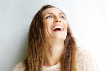Beautiful middle aged woman laughing against white background