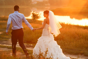 Fototapeta na wymiar groom and bride is walking on the background beautiful sunset