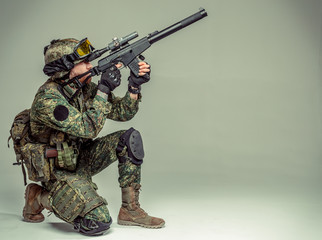 Special forces soldier with rifle on grey background