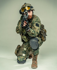 Special forces soldier with rifle on grey background