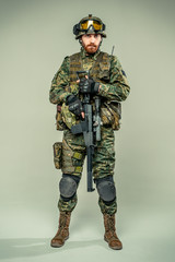 Special forces soldier with rifle on grey background