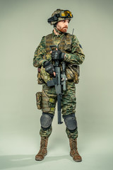 Special forces soldier with rifle on grey background