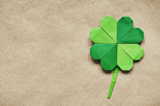 Green origami paper shamrock clover leaf on eco paper background. St. Patrick's Day greeting postcard template. Space for copy, text, lettering.