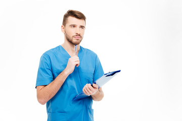 Pensive male doctor standing with clipboard