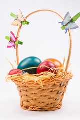 Easter eggs in wicker basket on white
