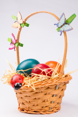 Easter eggs in wicker basket on white