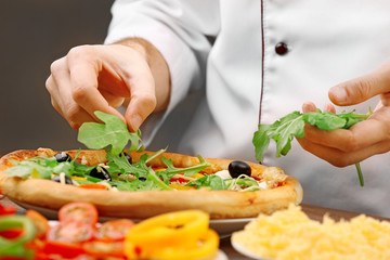 Cook making delicious pizza at the restaurant, close-up
