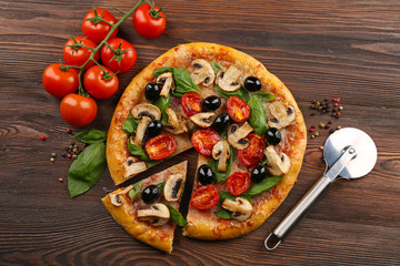 Sliced delicious tasty pizza with vegetables on wooden table