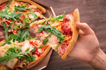 Piece of fresh pizza in hand closeup