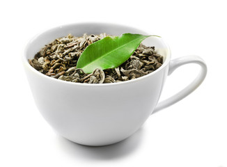 Cup with dry tea and green leaf, isolated on white