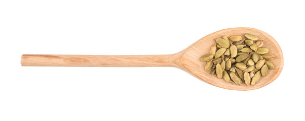Cardamom seeds in the wooden spoon on white background
