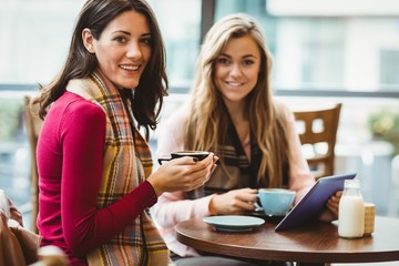Friends using tablet together in cafe