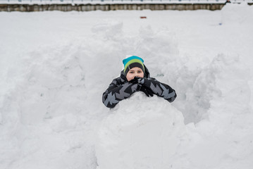 Fototapeta na wymiar Teen boy sitting in homemade snow fort