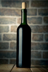 Wine bottle on a wooden table with bricks wall background