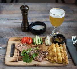 Tasty meat on a board with snacks and beer, top view. Photo for the menu