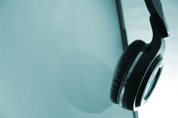 Headphones hanging on a screen. Empty copy space for editor's text.