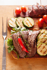 Delicious beef steak with vegetable over wooden table close-up