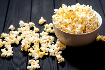 cheese popcorn in the bowl with a glass of cola or beer and potato chips on the wooden background