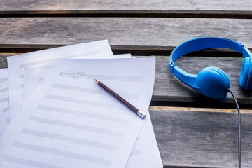 composing music with blue headphone and on the wooden desk