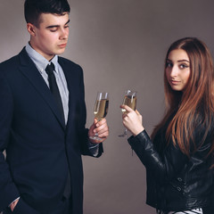 Portrait young couple with glass of champagne, wear evening dress and suit, glamour vogue style, sensual looking at camera, sitting indoors