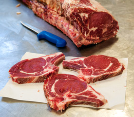Raw rib eye steak slices on table