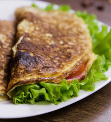 Healthy eating for breakfast. Scrambled eggs with oatmeal , ham and cheese , lettuce and tomatoes inside. 