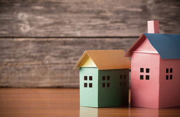 A paper houses stands over a wooden background.