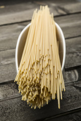 Spaghetti crudi dentro piatto bianco lungo su sfondo tavolo in legno 