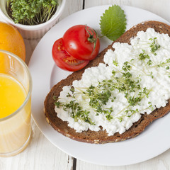 healthy spring summer low fat breakfast with orange juice,coffee,bread,cottage cheese, cress and tomatos at white wooden table