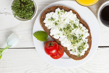 healthy spring summer low fat breakfast with orange juice,coffee,bread,cottage cheese, cress and tomatos at white wooden table