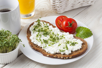 healthy spring summer low fat breakfast with orange juice,coffee,bread,cottage cheese, cress and tomatos at white wooden table