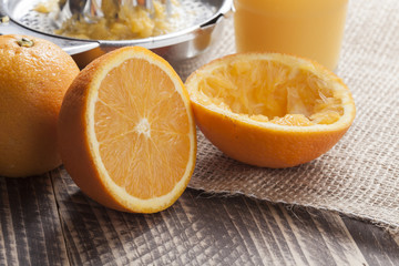 fresh squeezed orange juice for breakfast with glass and squeezer on vintage wooden table in...