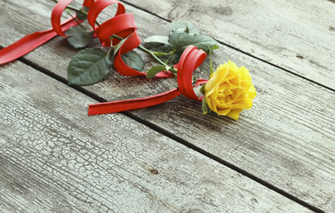Yellow rose with red ribbon