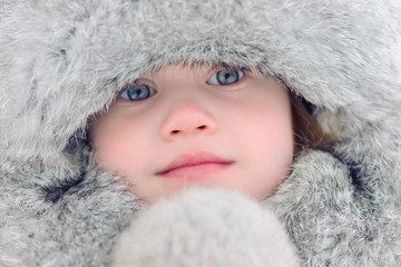 A child in a fur cap. In the winter park - 103642314